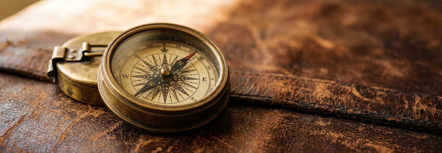 A brass compass resting on worn leather